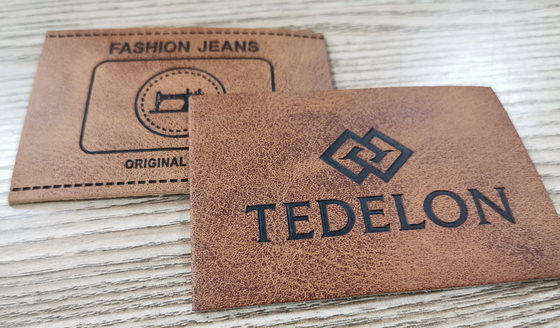 A cor feita sob encomenda gravada dos remendos de couro do plutônio do logotipo costura na roupa
