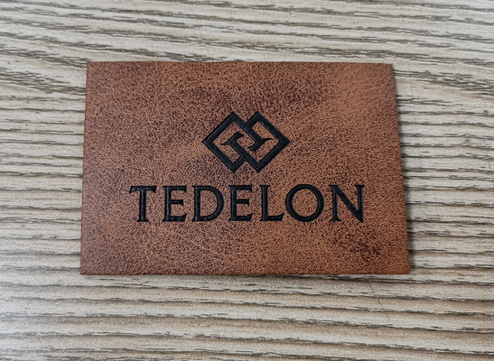 A cor feita sob encomenda gravada dos remendos de couro do plutônio do logotipo costura na roupa