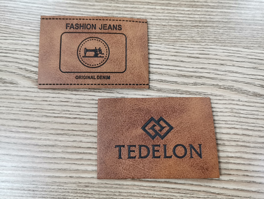 A cor feita sob encomenda gravada dos remendos de couro do plutônio do logotipo costura na roupa